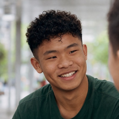 A teenager smiling under a rainy walkway